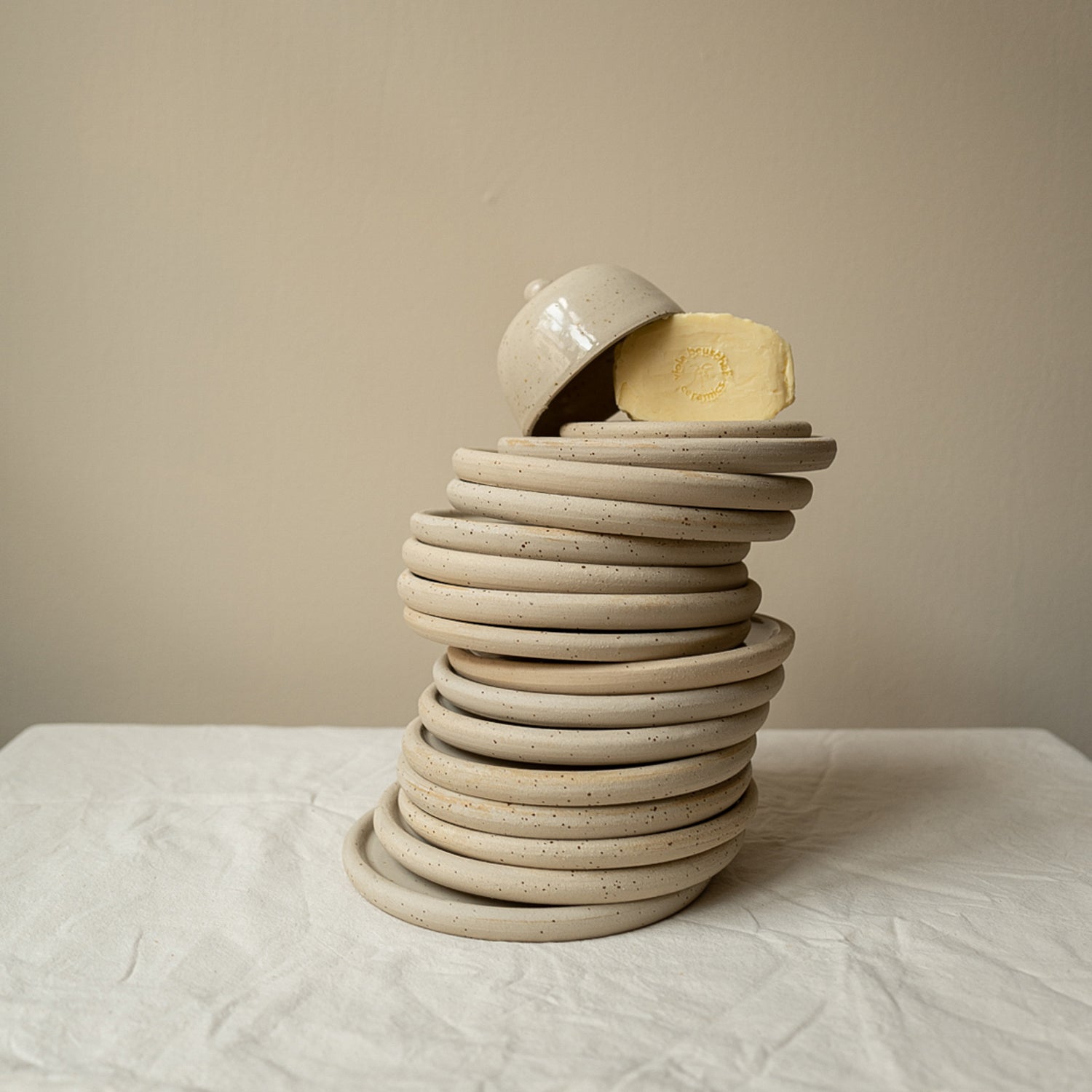 Shows the Butter Dishes from a cooperation between Viola Beuscher Ceramics and Maison Palme. In the picture you can see many coasters stacked with an attachment and a butter on top.